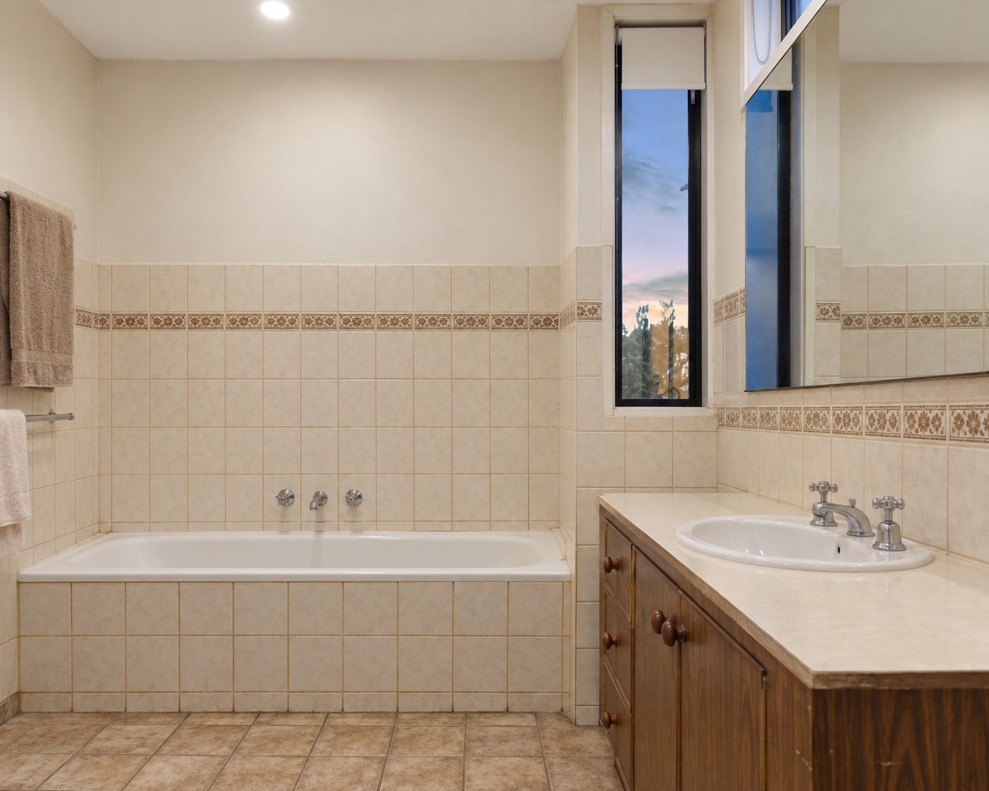 AI-illustratie vóór renovatie: dezelfde badkamer met crèmekleurige wandtegels, een ingebouwd bad en een houten wastafelmeubel.